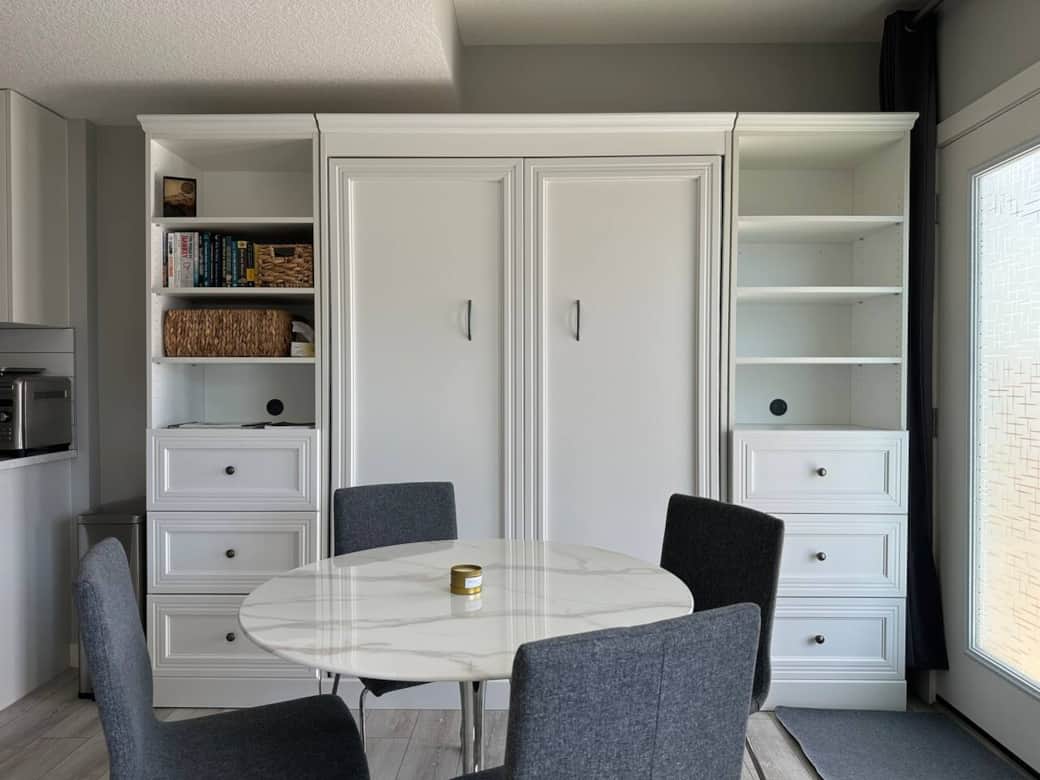 Bright and modern living space with a sleek Murphy bed, smart storage, a cozy desk setup, and comfortable seating. Perfect for relaxing, working, or enjoying a quiet night in.