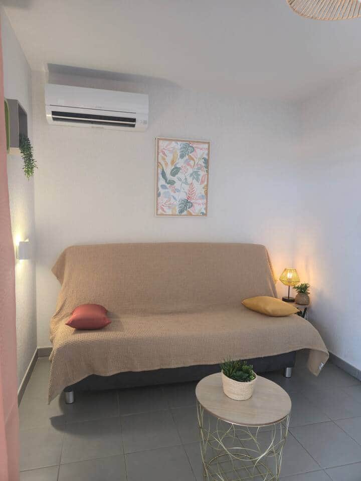 Salon cosy et lumineux avec canapé convertible, climatisation et déco moderne. Idéal pour se détendre en famille ou profiter d’une soirée télé après une journée à la plage d’Argelès-sur-Mer.