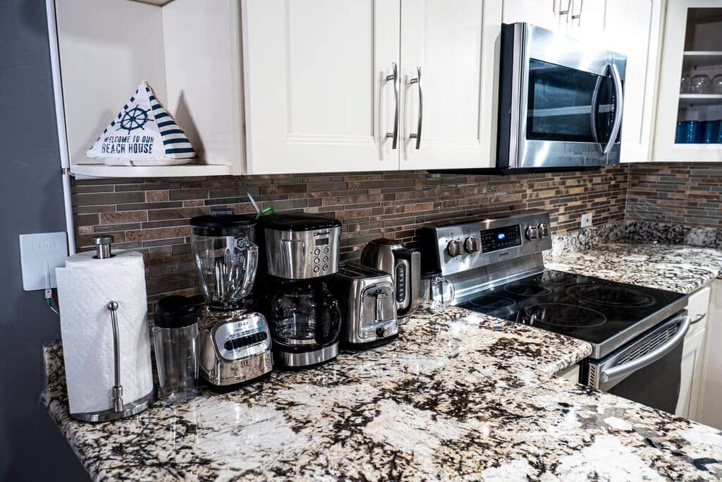 Kitchen - Coffee going early, with a stone backsplash, coffee maker, toaster, microwave and a full s