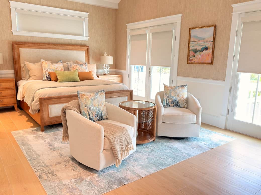 A spacious upstairs primary suite with a king bed, vaulted ceiling, smart TV, ceiling fan, and a private sitting area. Finished in a refined coastal-modern style, it also features a private balcony overlooking the pool and a luxurious en-suite bath.