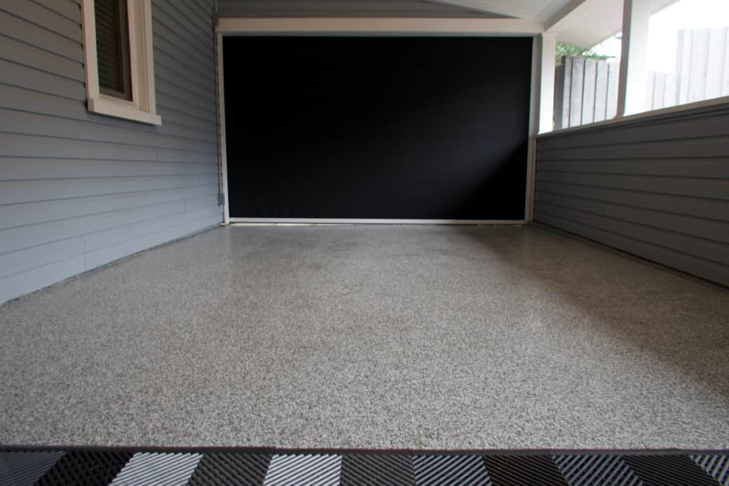 Epoxy floored carport with a motorized privacy screen that acts as a garage door.