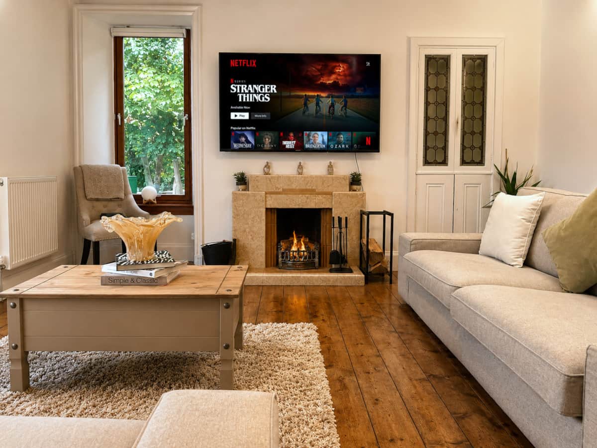 Living room with a wood-burning fire, deep sofas and wooden floorboards.
