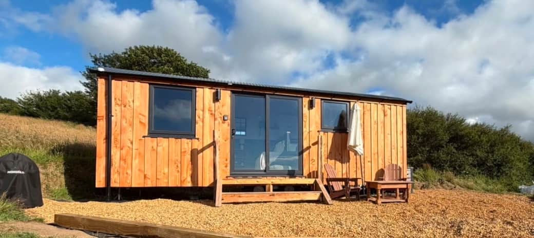 Cosy shepherd hut exterior with countryside backdrop Cosy shepherd hut exterior with countryside backdrop