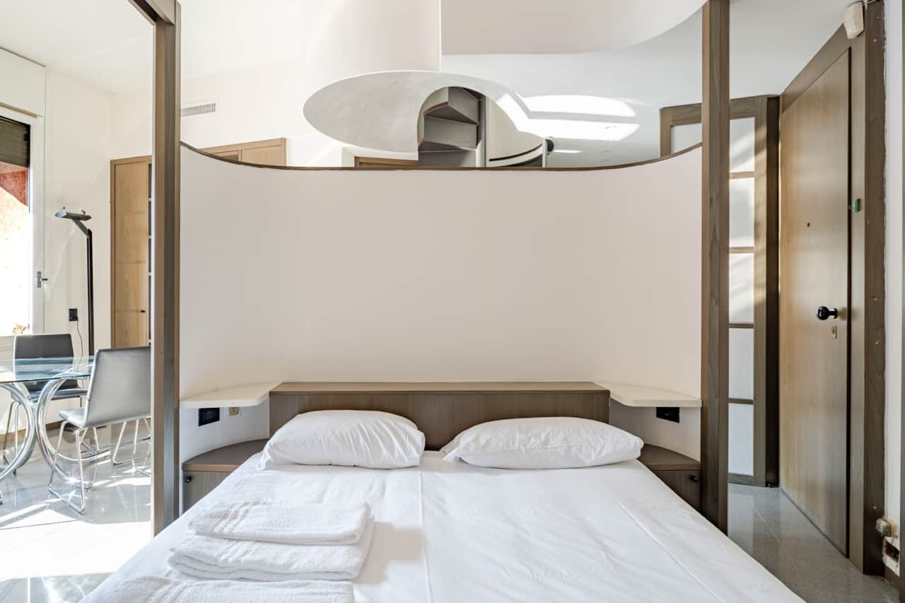 Bedroom with white bed and shelves, in Brera, Milan