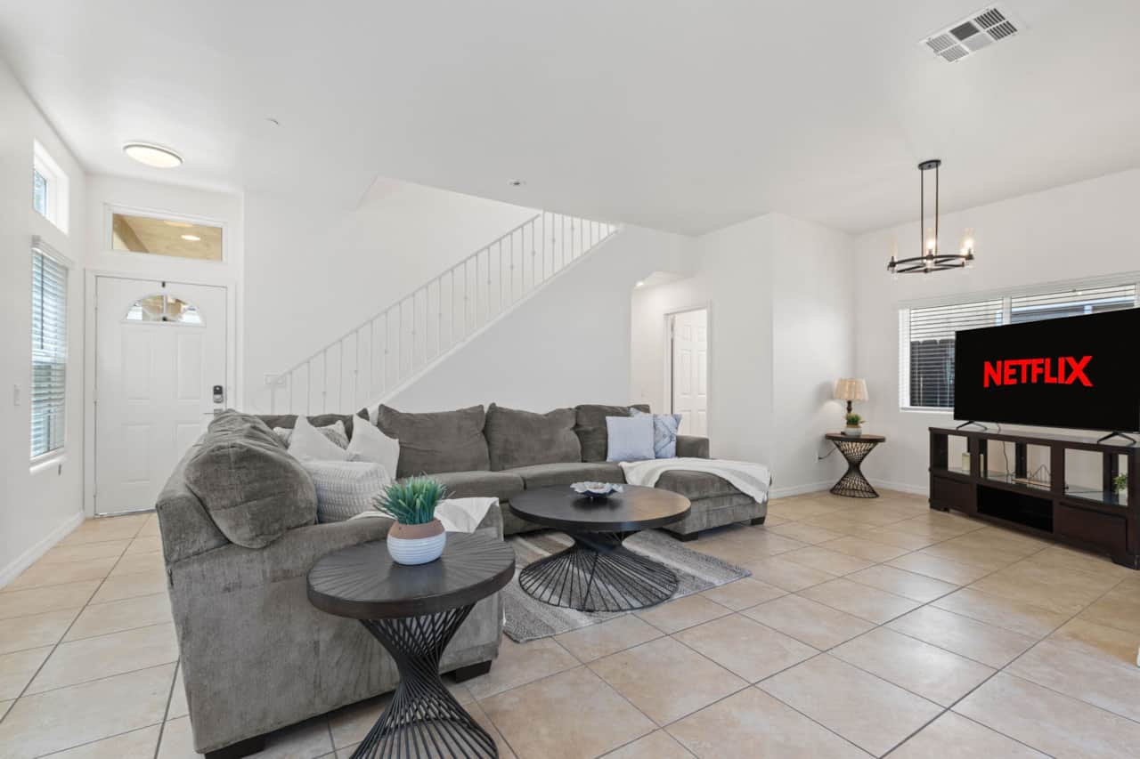 Bright living room with a cozy sectional, smart TV, modern decor, and plenty of natural light.