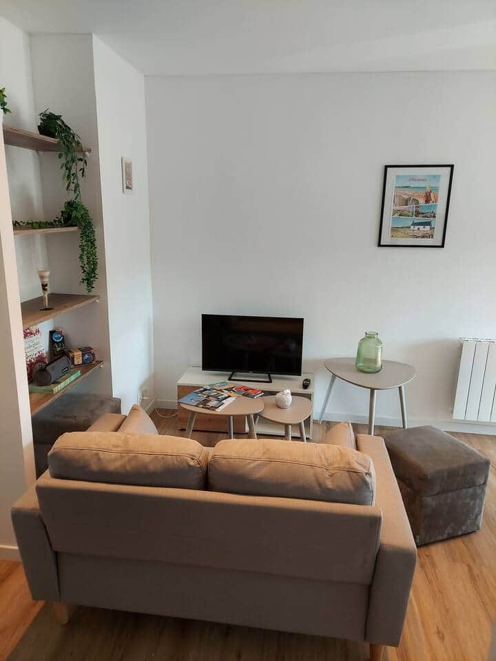 Petit salon, avec canapé 2 places, 2 poufs / rangement, et TV + Freebox