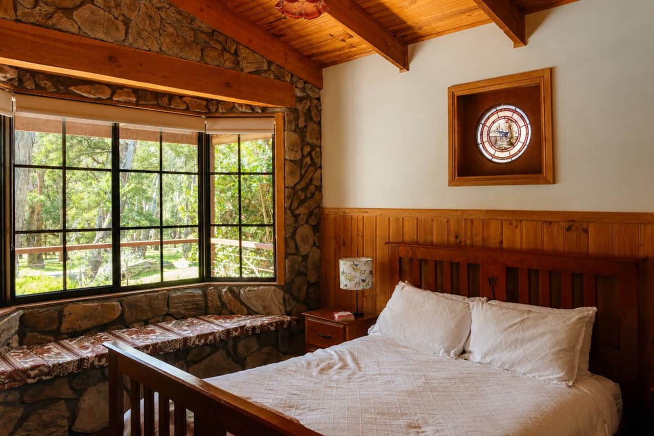 A cosy main bedroom with a queen bed, warm timber features and a beautiful bay window overlooking the garden.