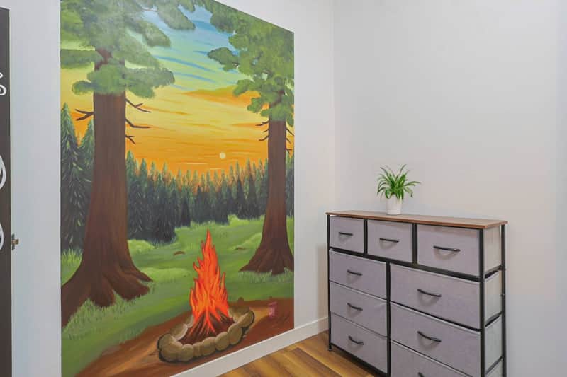 Mural chaleureux de feu de camp au coucher du soleil — peint par une artiste locale.