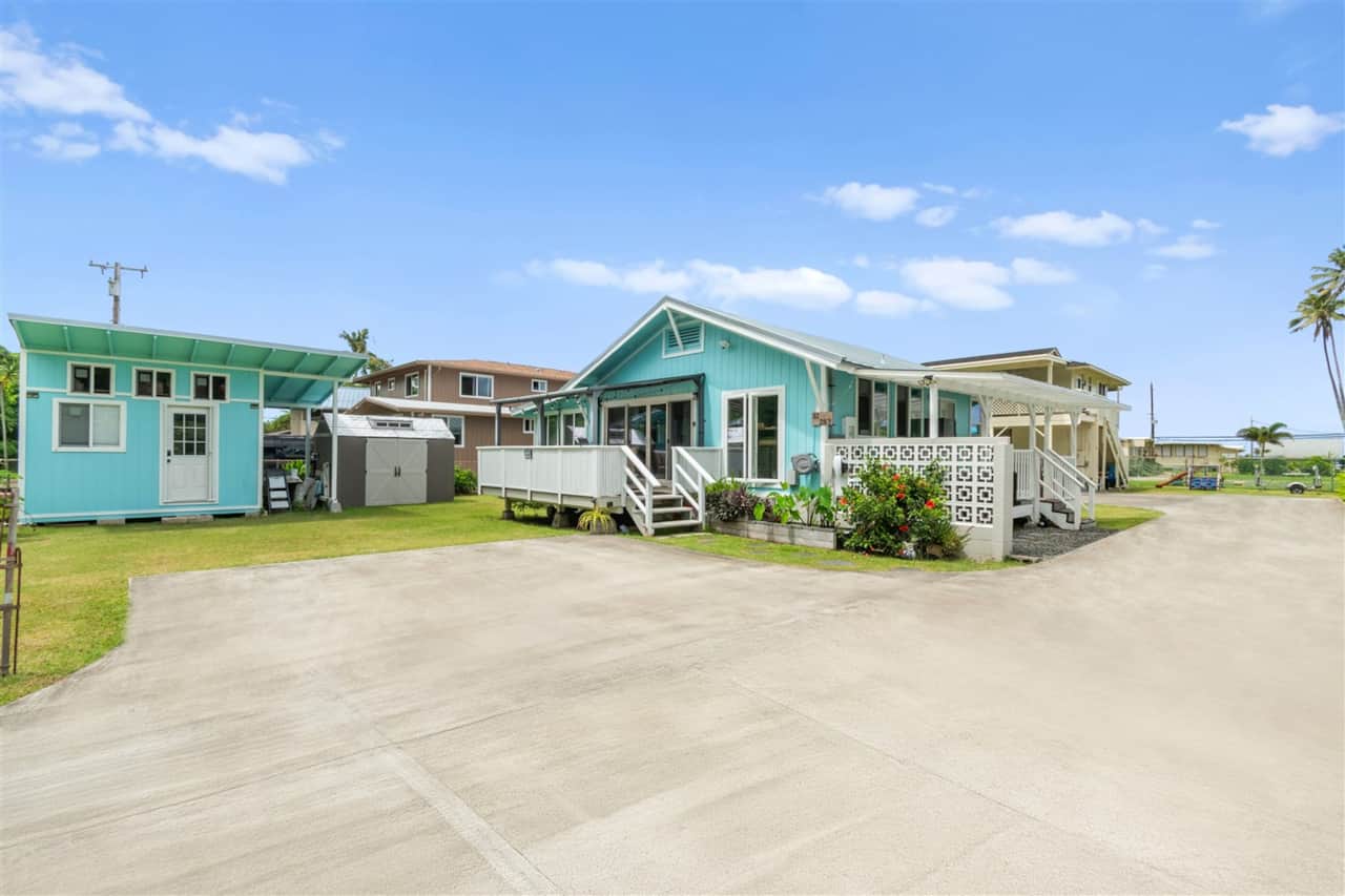 Light blue single-story home with a white deck and driveway
