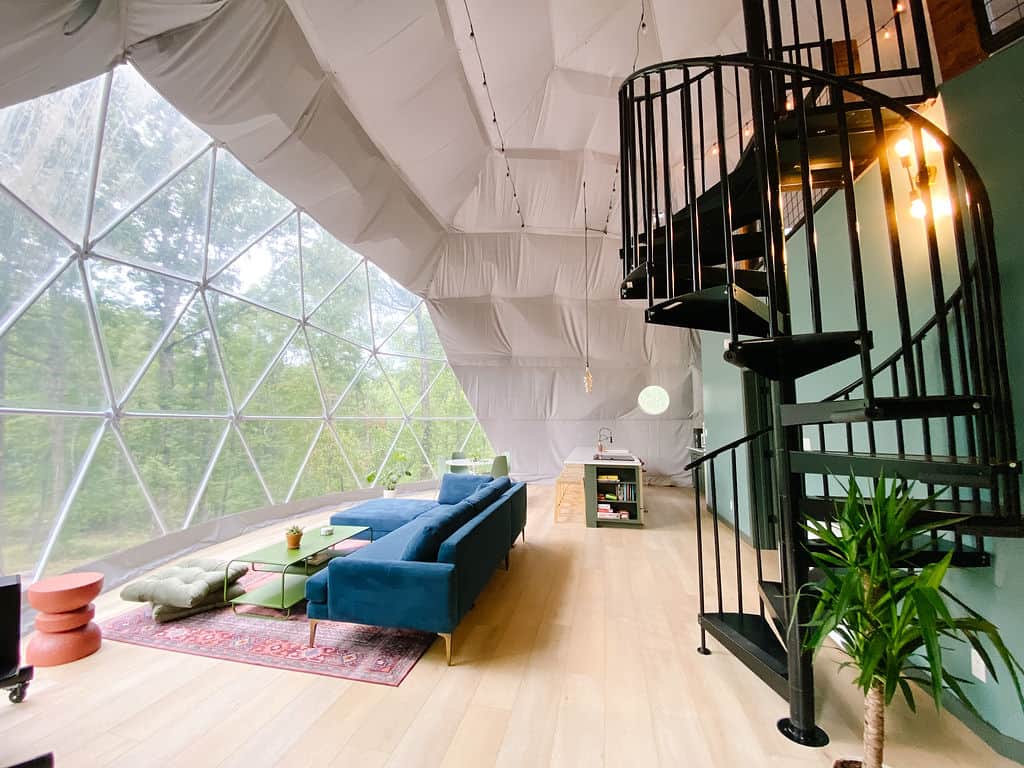 Spacious family living room and loft stairs inside the Lake Martin glamping dome