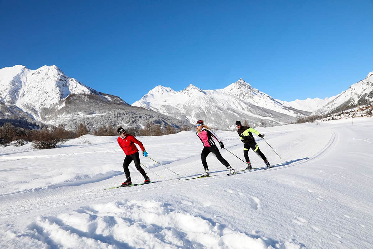 Ski de fond en groupe sur les pistes enneigées face aux sommets des Alpes, Serre Chevalier Vallée