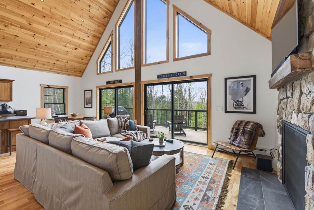 Vaulted great room with stone fireplace, forest views and deck access