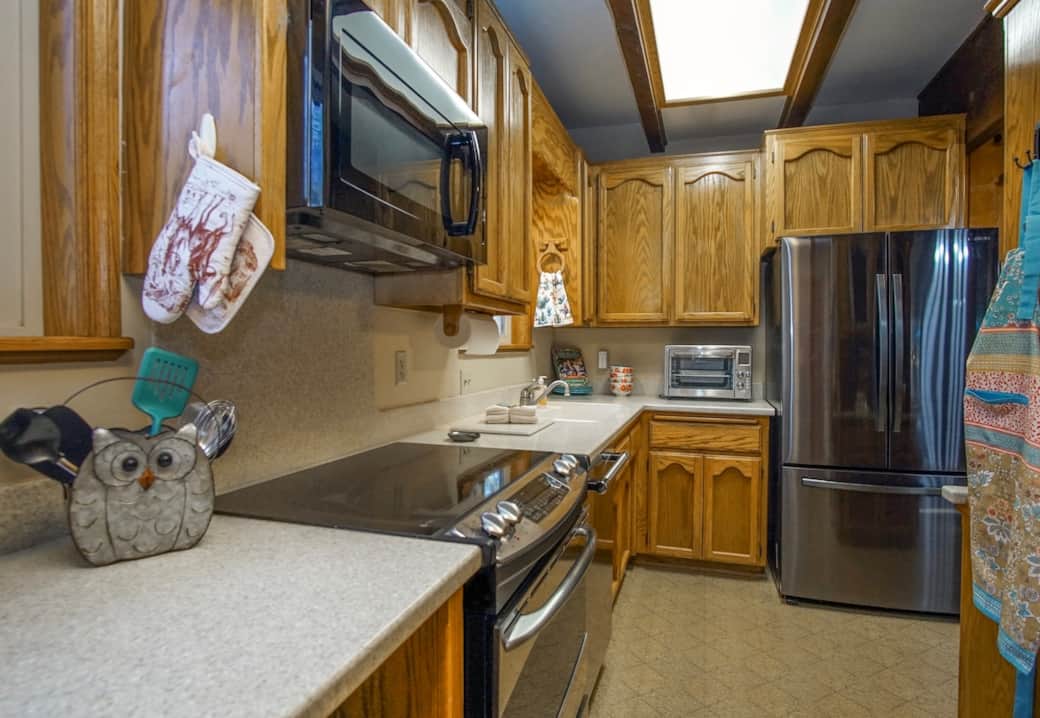 A bright, fully-equipped galley kitchen featuring classic oak cabinetry and stainless appliances. Start your morning right at our complimentary coffee station—complete with whole roasted beans, a French press, K-cups, and creamers!