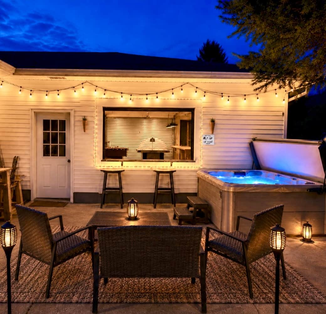 Private patio with hot tub, grill, glowing lights, and indoor/outdoor entertaining space. Private patio with hot tub, grill, glowing lights, and indoor/outdoor entertaining space.