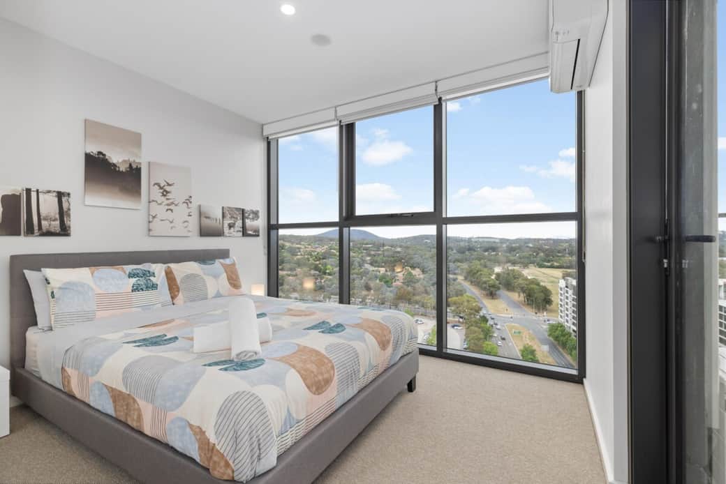 Experience tranquility in our second bedroom, a perfect sanctuary for relaxation. The large window allows for ample natural light, enhancing the room's airy feel. The bed, dressed in soothing patterns, invites you to unwind after a day of exploration