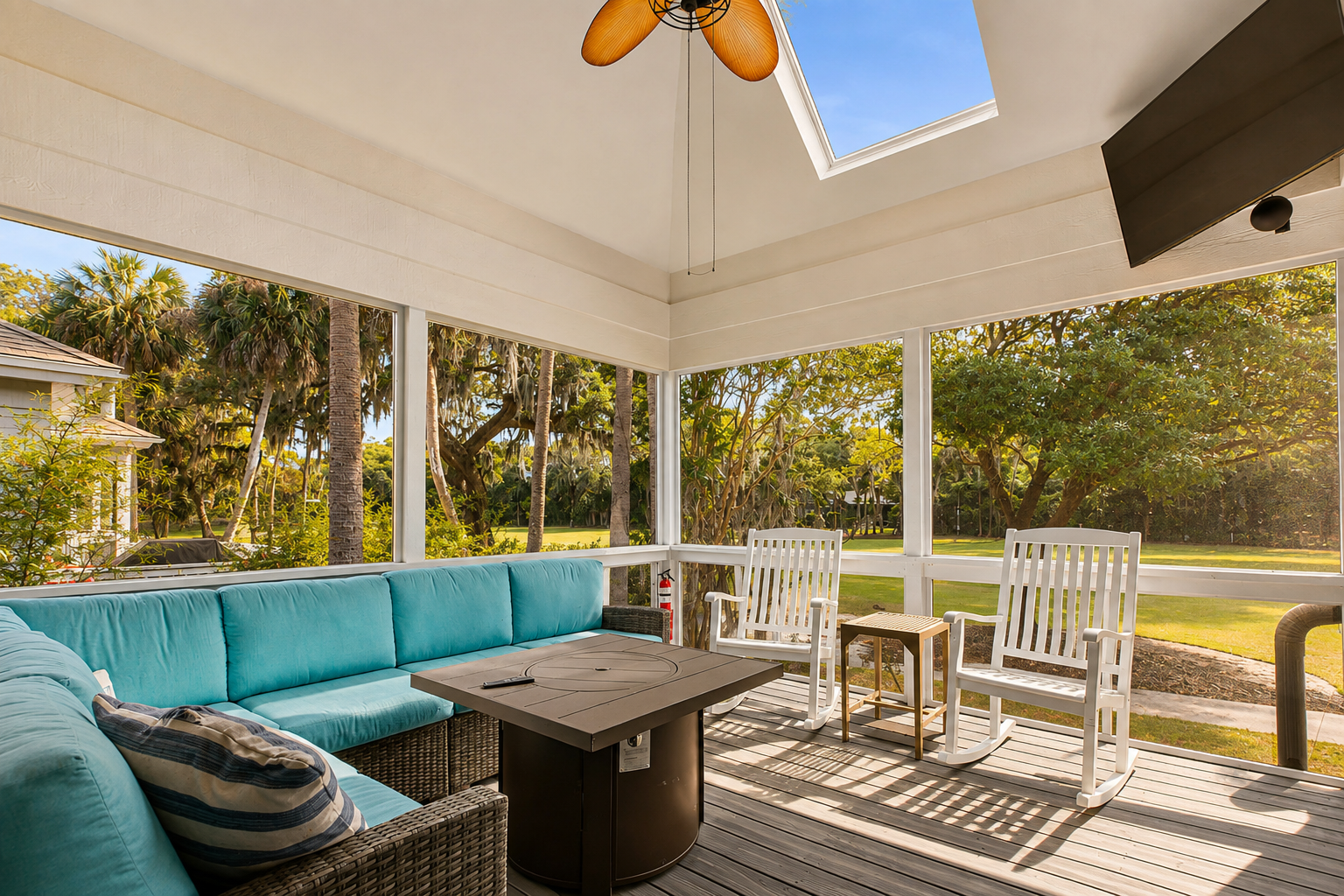 Bright screened patio with a cozy sectional, rocking chairs, TV, and beautiful outdoor views.
