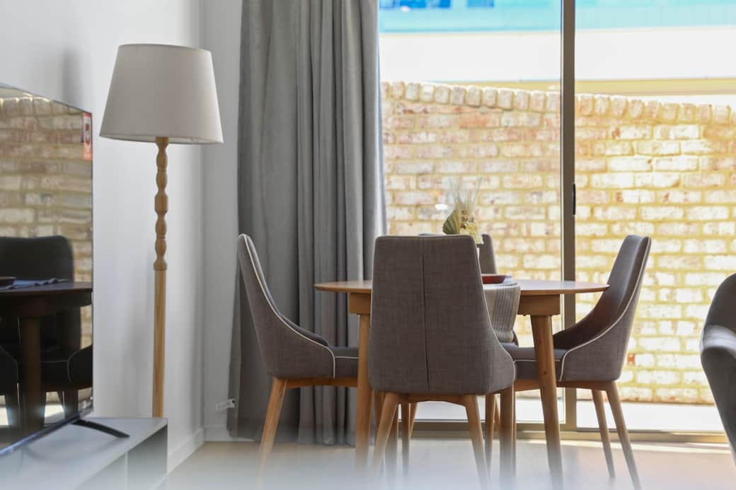 Dine in style with our elegant dining area, featuring a sleek wooden table and comfortable chairs. The soft natural light filtering through the window creates a serene ambiance for delightful meals.