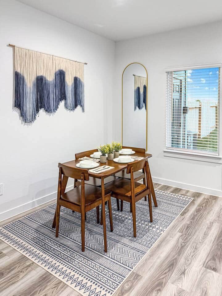 Beautifully designed Bohemian art surrounding a wooden dining room table that can be used for eating or a desk while enjoying the open space downstairs.