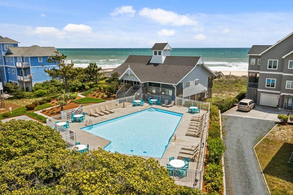 Oceanfront pool with clear blue water, lounge chairs and tables for relaxing and sunbathing.