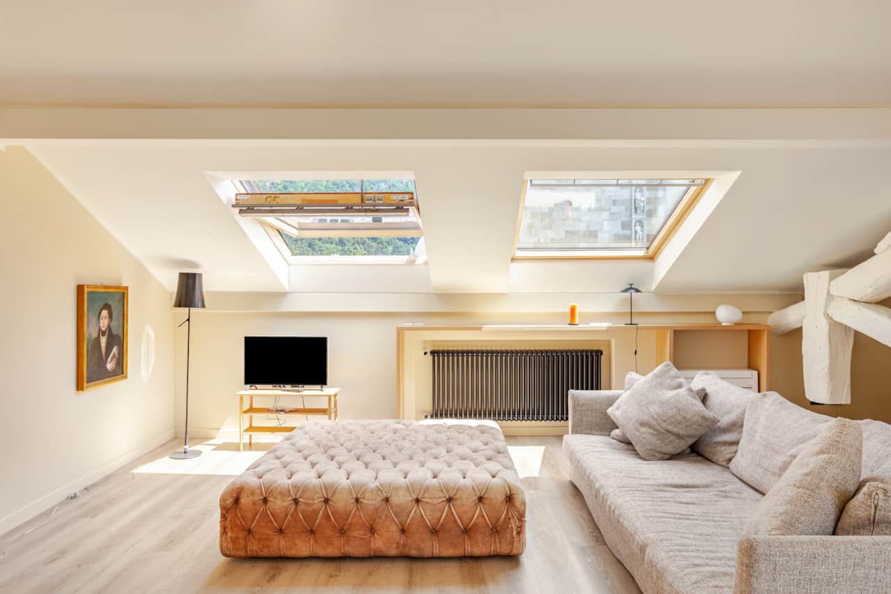 Wohnzimmer mit Sofa, Pouf und Dachfenstern