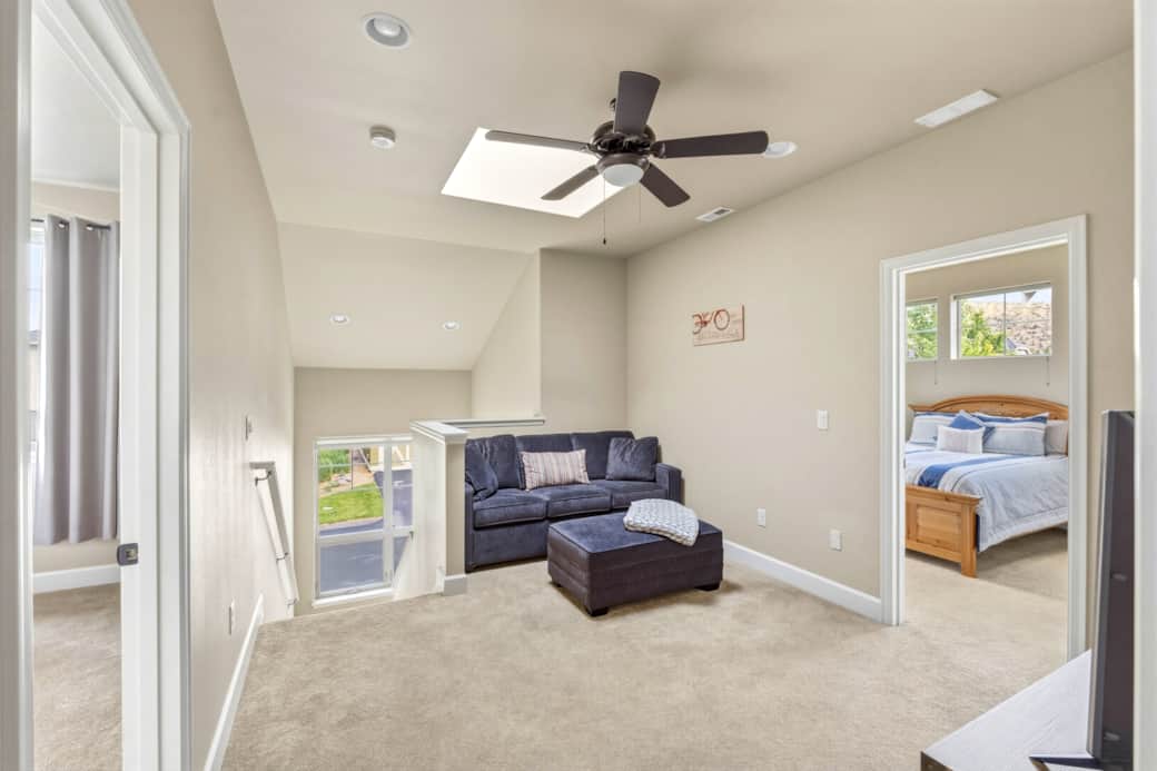 Skylit loft with queen sofa bed, TV, ottoman, and access to both upstairs bedrooms.