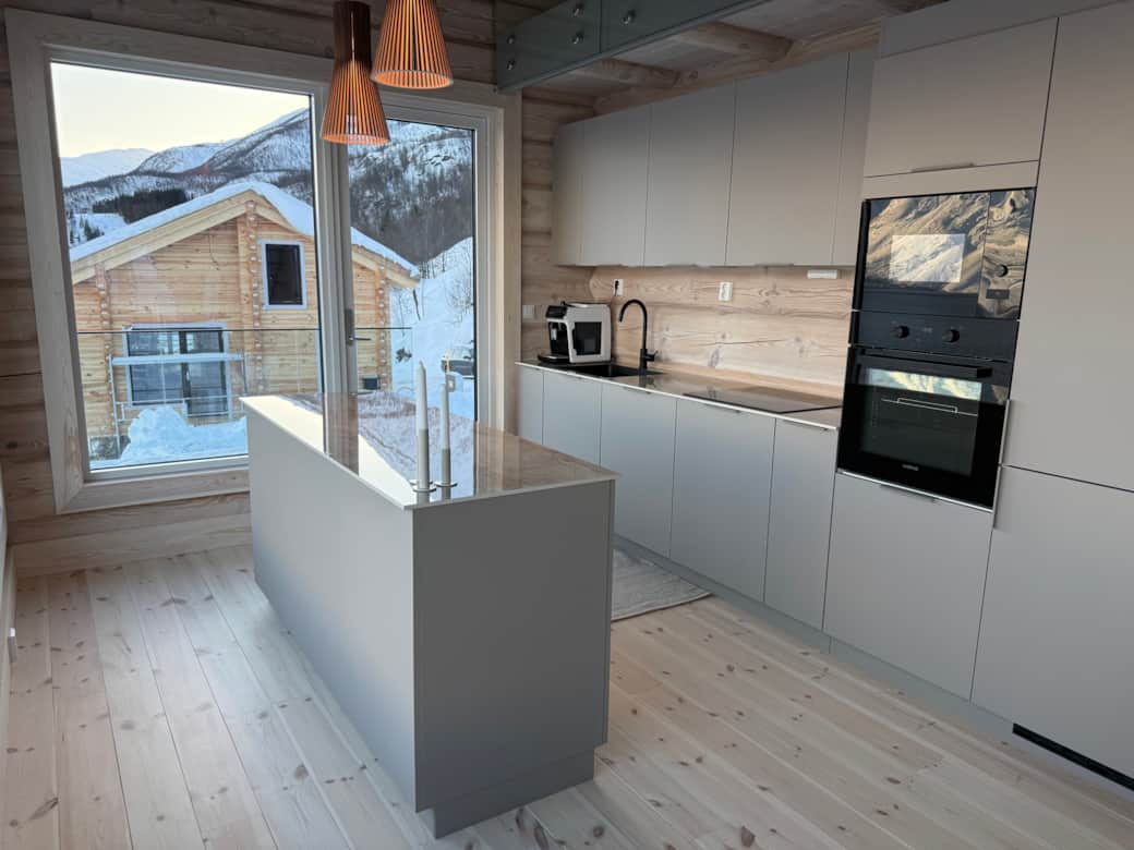 Moderne Küche mit Kochinsel und Fjordblick im Blockhaus Moderne Küche mit Kochinsel und Fjordblick im Blockhaus
