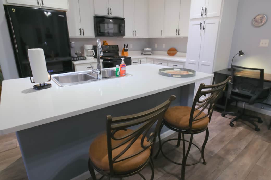 Dedicated workspace between kitchen and dining, equipped with desk, chair, and lamp.