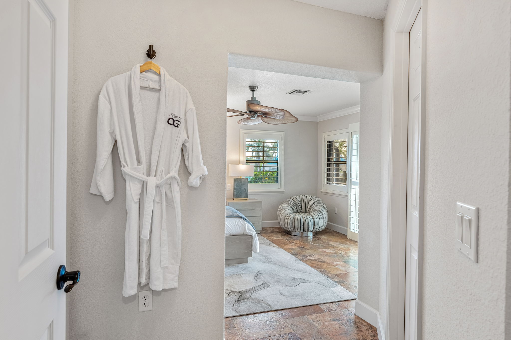 Step into comfort with plush robes, serene decor & pool view bedroom bliss.