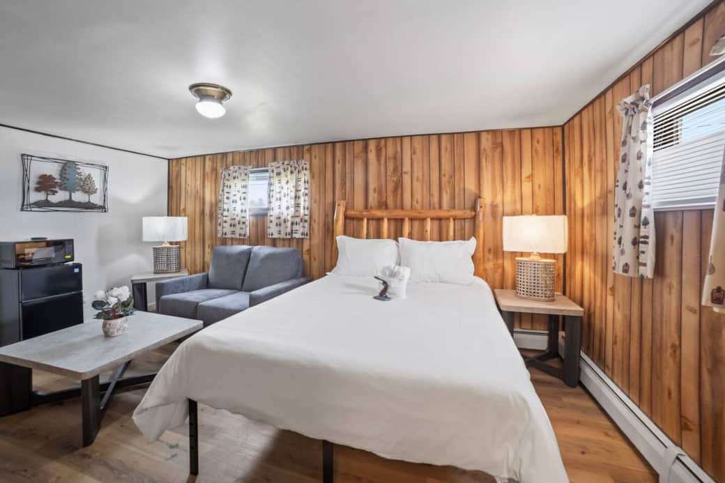 Inviting bed framed by rich wooden walls, accented with soft lighting for a peaceful night’s sleep.