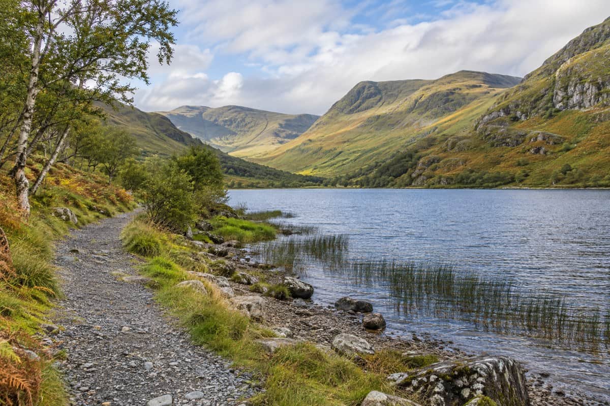 AI illustration: lochside track below rounded Highland hills