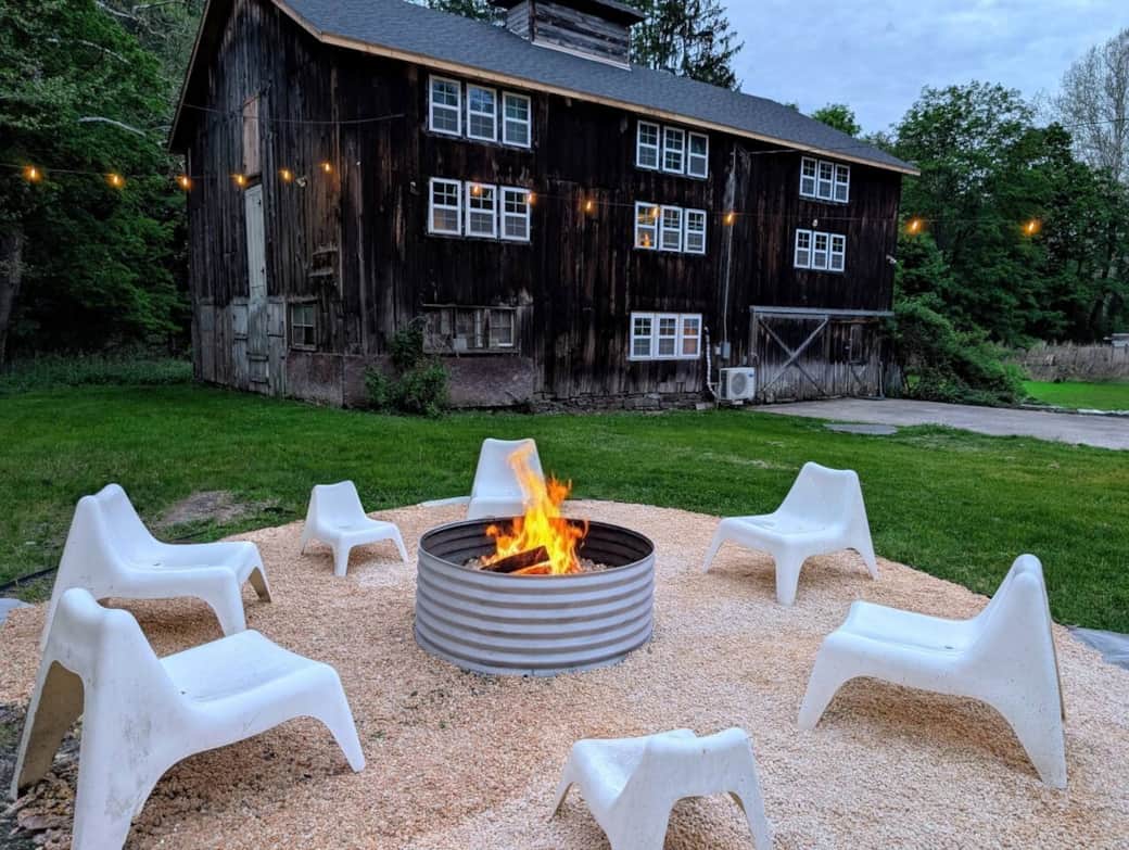 The firepit is in the backyard along with the hot tub and the deck of the house looking to the barn in back and creek to the left.