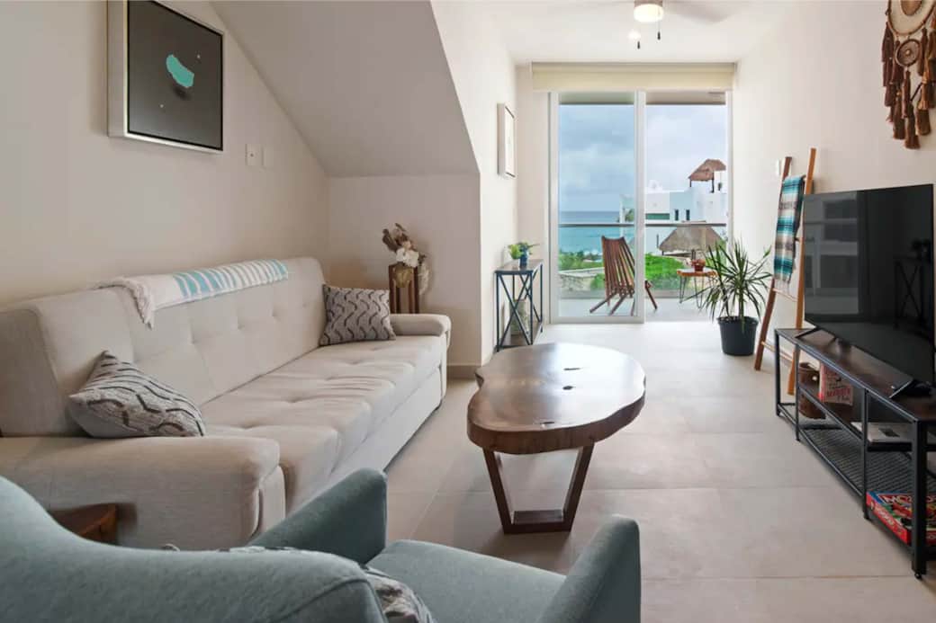 Seaside comfort: Stylish couch, cozy bed, smart TV, Caribbean backdrop - perfect escape!