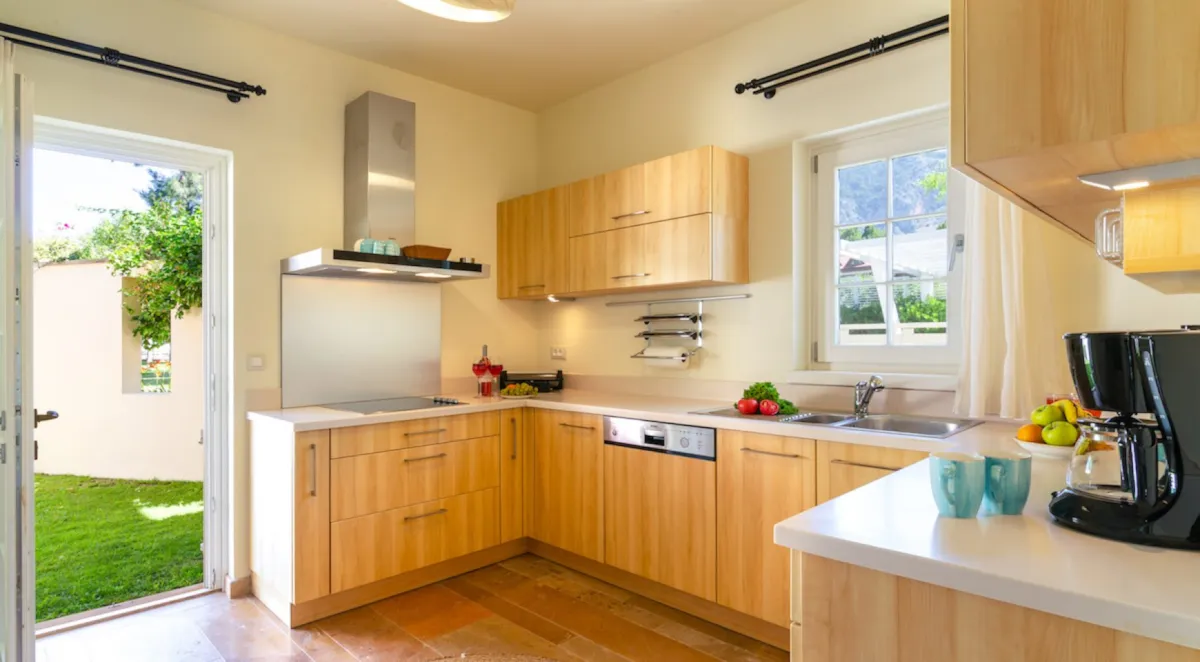 Modern kitchen with wooden cabinets, sink, and appliances, featuring a view of the garden.