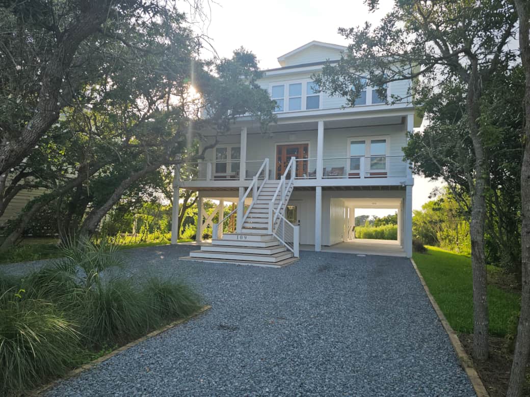 Charming Low Country beach home with wide front porch, custom trim, nestled among live oak trees.