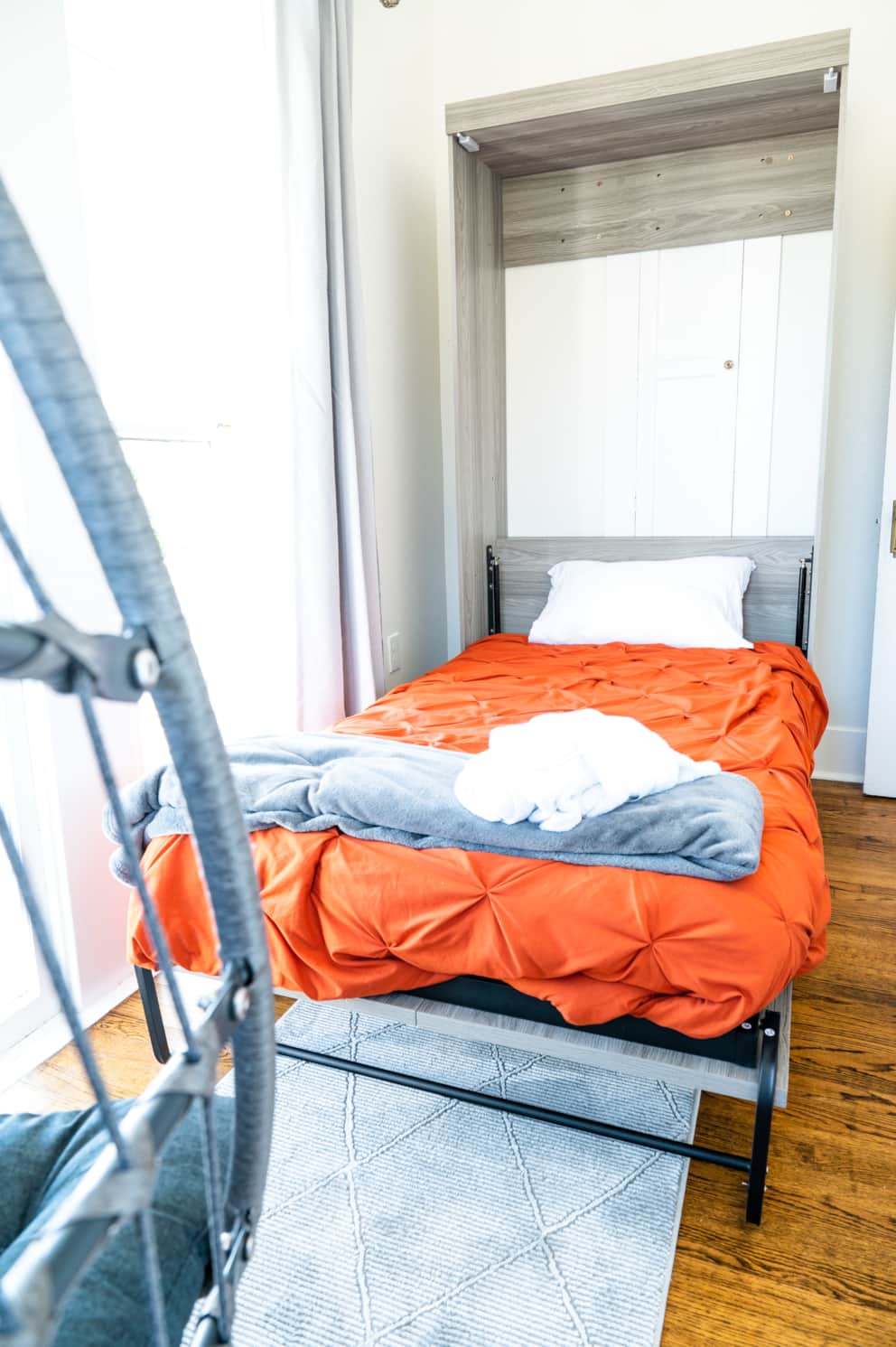 Wide view of the twin bedroom with swing chair and cozy layout at White Magnolia Galveston
