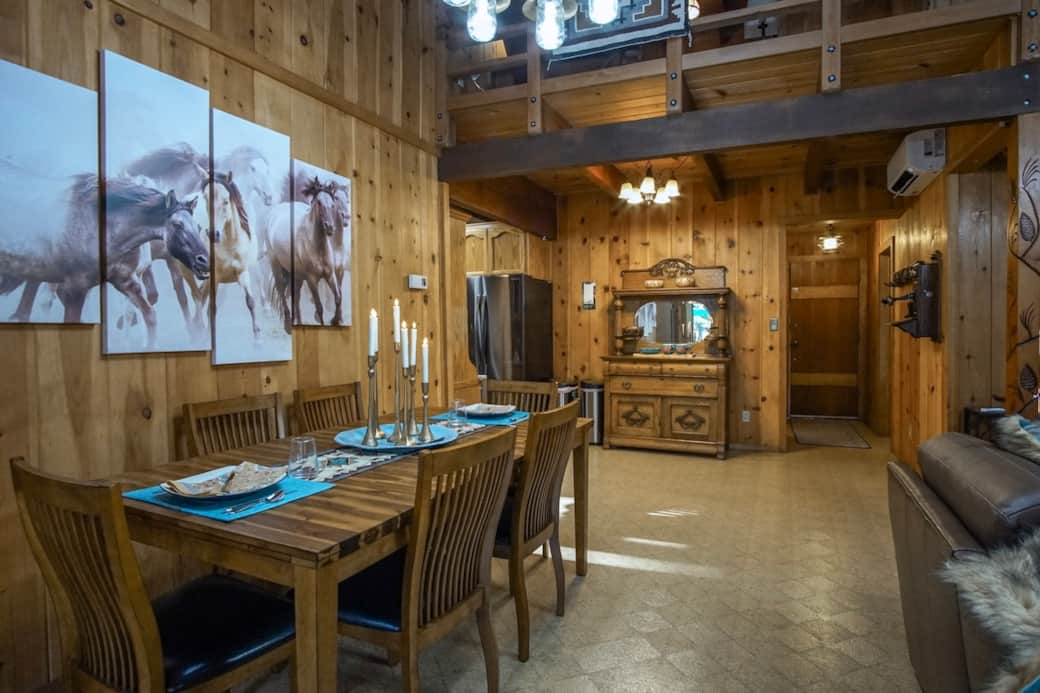 Gather for slow dinners and lingering conversations in this rustic-elegant dining space. Featuring warm wood walls, striking horse art, bold turquoise accents, and remote-controlled ambient candles to instantly set the perfect evening mood.