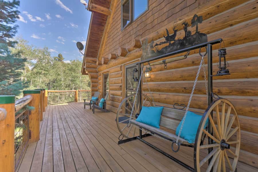 Wagon-wheel porch swing on the wrap-around log cabin deck