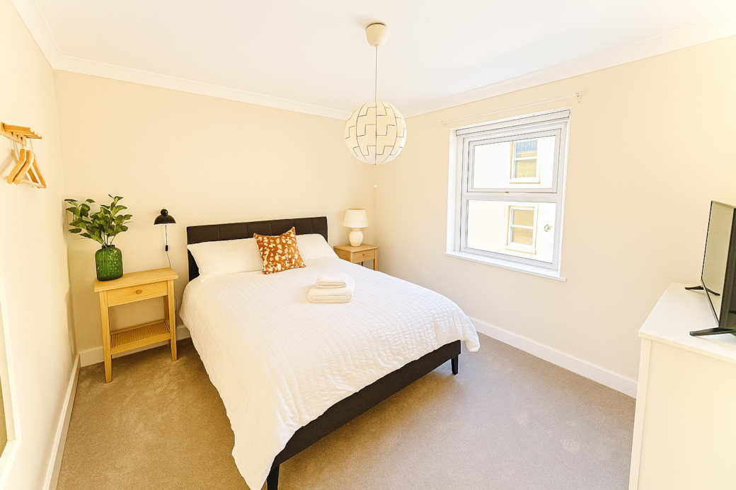 Bright, airy double bedroom with plush carpet and warm cream walls. Enjoy a comfy bed, TV and minimalist decor that invites relaxation. Space for a foldaway single bed. 