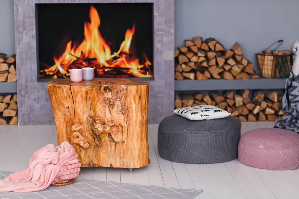 Scandinavian interior with fireplace stump table pile logs fire