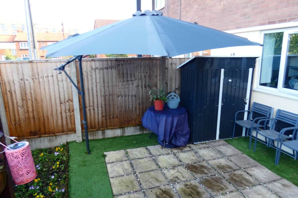 Private outdoor patio area at the front of the property, with garden furniture and parasol.
