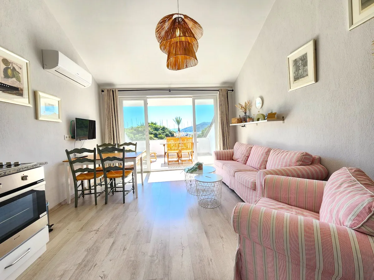 Living room featuring pink striped sofas, dining table, and a view of the outdoors, Apart Guney 4, Gocek.