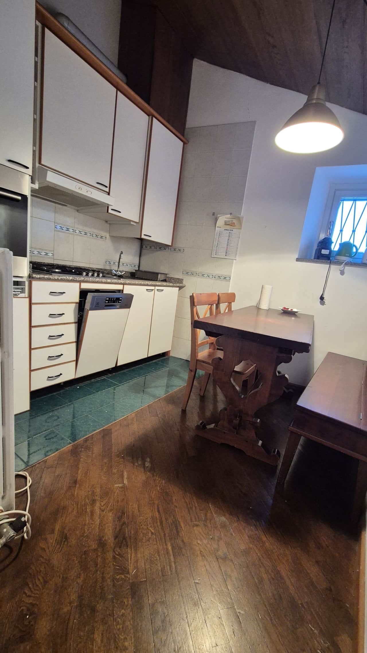Cocina con armarios blancos, horno y mesa con sillas