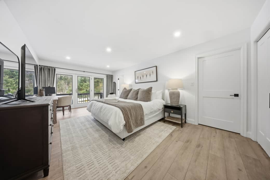 Primary suite with king bed, pond views, organic bedding, and private deck access.