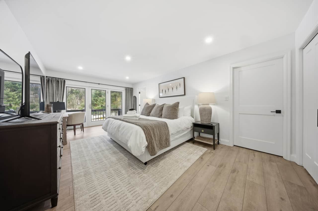 Primary suite with king bed, pond views, organic bedding, and private deck access.