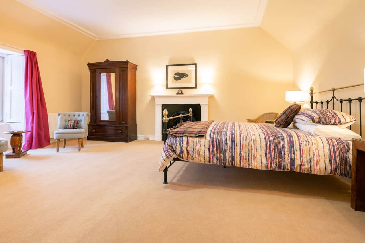 King bedroom with fireplace and seating in Aros Mains Apartment