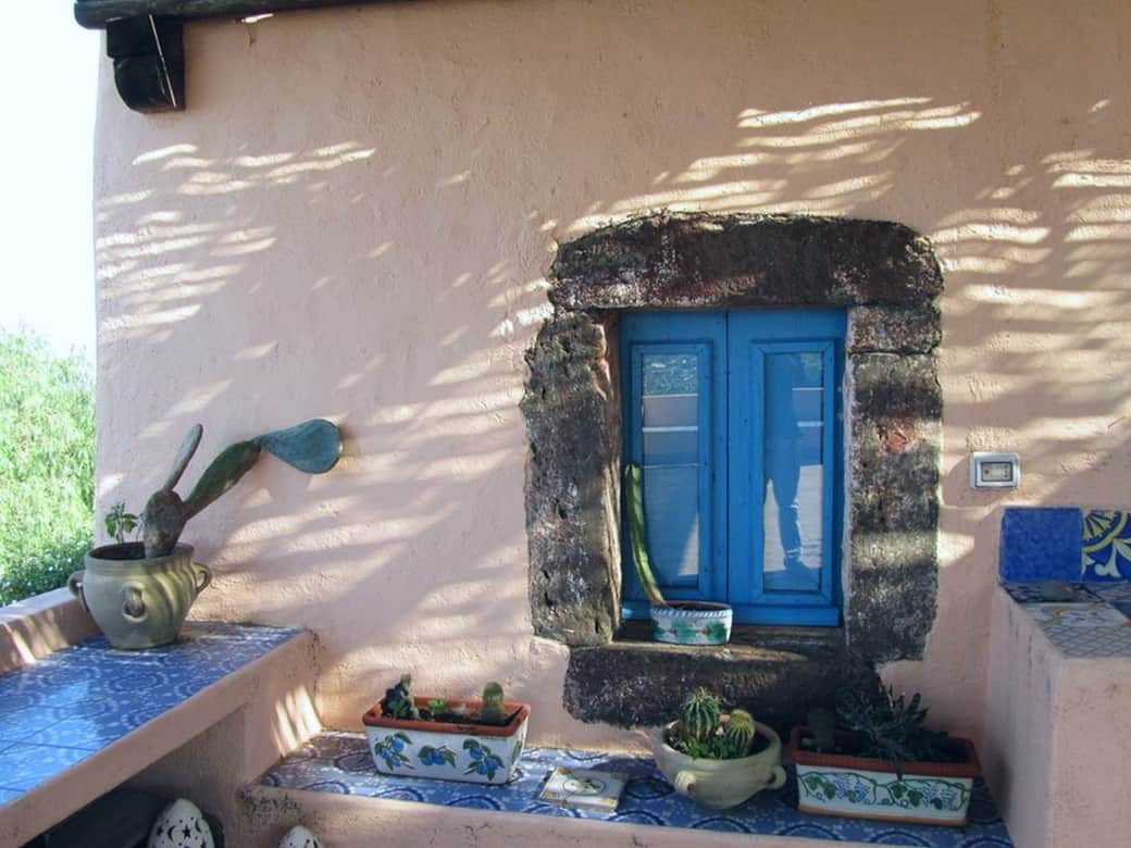 Dettaglio architettonico eoliano con finestra azzurra e bordi in pietra lavica Dettaglio architettonico eoliano con finestra azzurra e bordi in pietra lavica