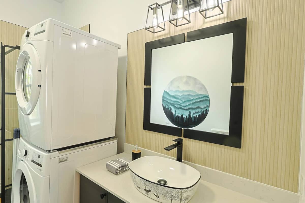 Buanderie pratique avec laveuse-sécheuse superposées, intégrée à une salle de bain stylée.