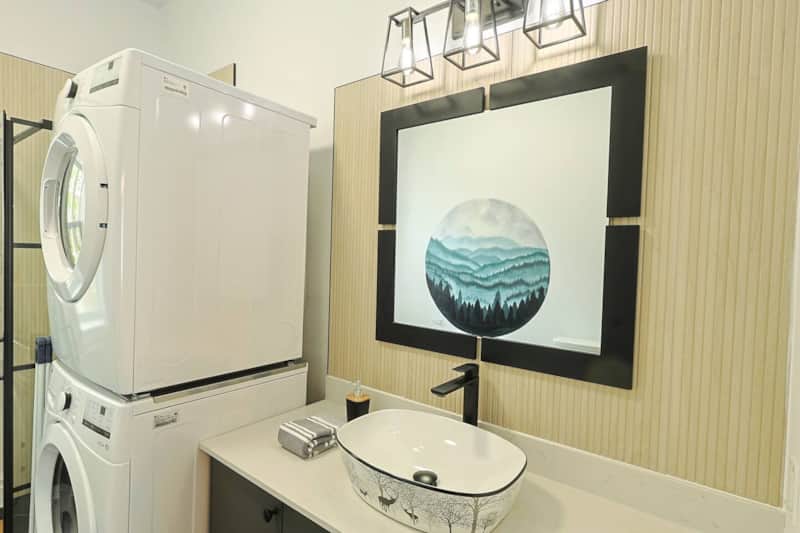 Buanderie pratique avec laveuse-sécheuse superposées, intégrée à une salle de bain stylée.
