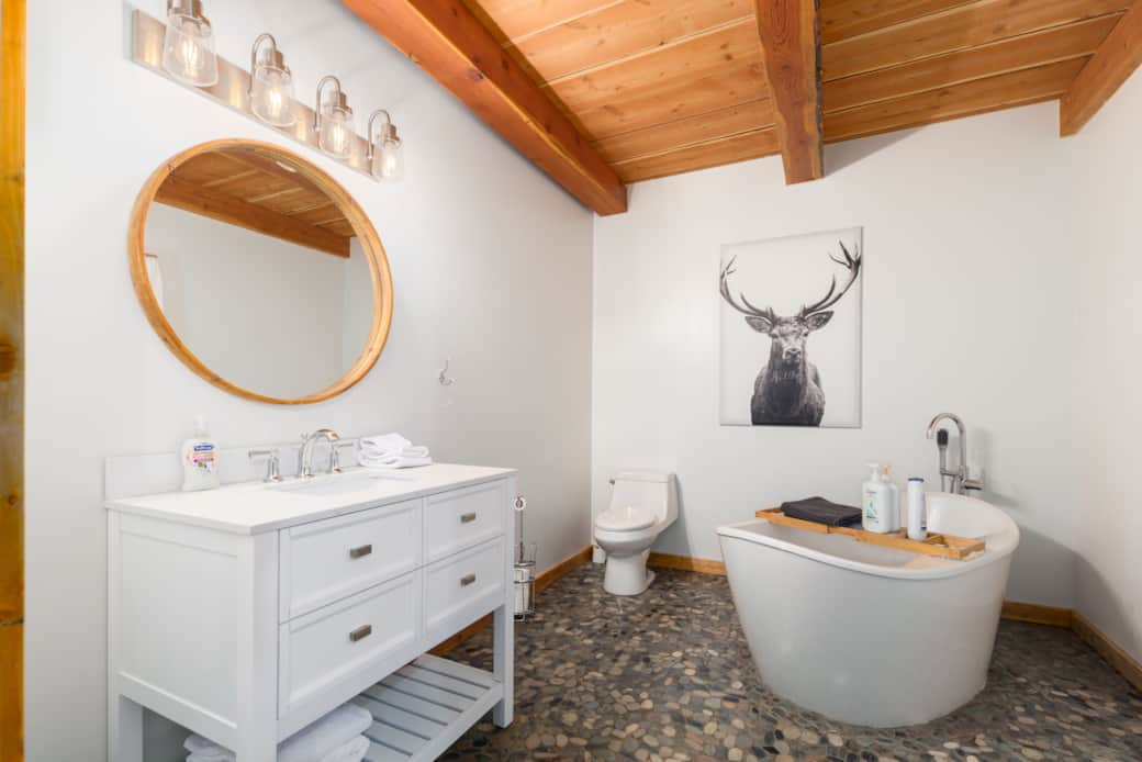 'Spa' bathroom with freestanding soaker tub, custom stone flooring, and warm wood ceiling 'Spa' bathroom with freestanding soaker tub, custom stone flooring, and warm wood ceiling