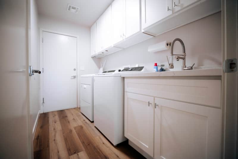 Laundry room with a utility sink, counter space and cabinets.